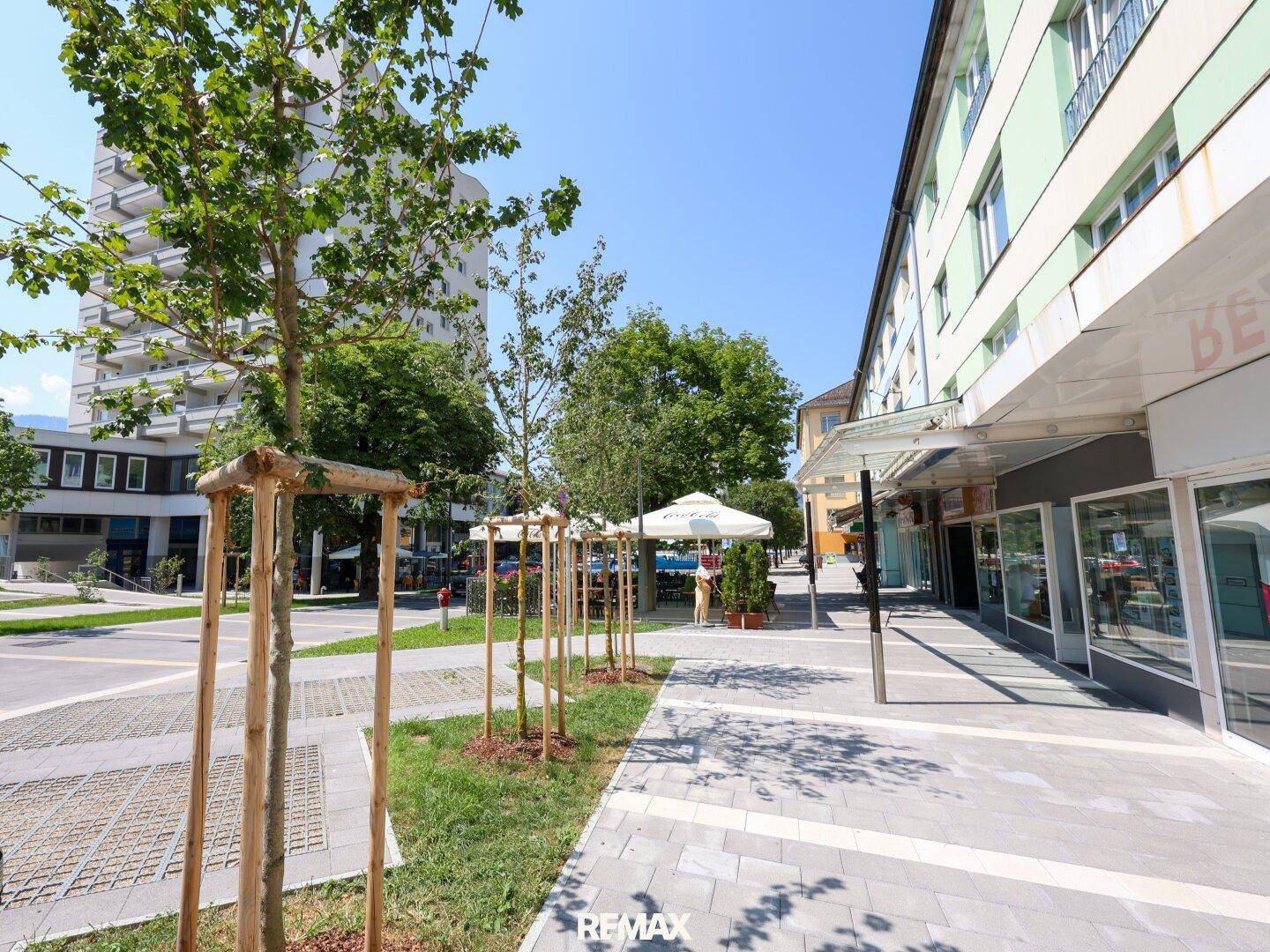 Weitläufige Ansicht einer städtischen Straße mit Bäumen, Gebäuden und einem sonnigen Ambiente.