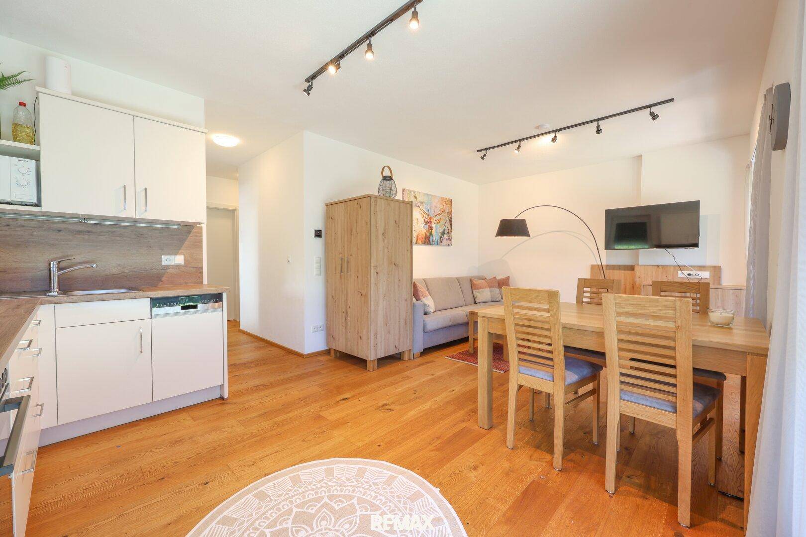 Offener Wohn- und Essbereich mit Holzboden, Esstisch und gemütlichem Sofa.
