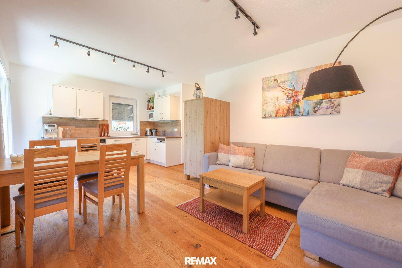 Geräumiger Wohn- und Essbereich mit Holzboden, Sofa und Blick auf die Küche.