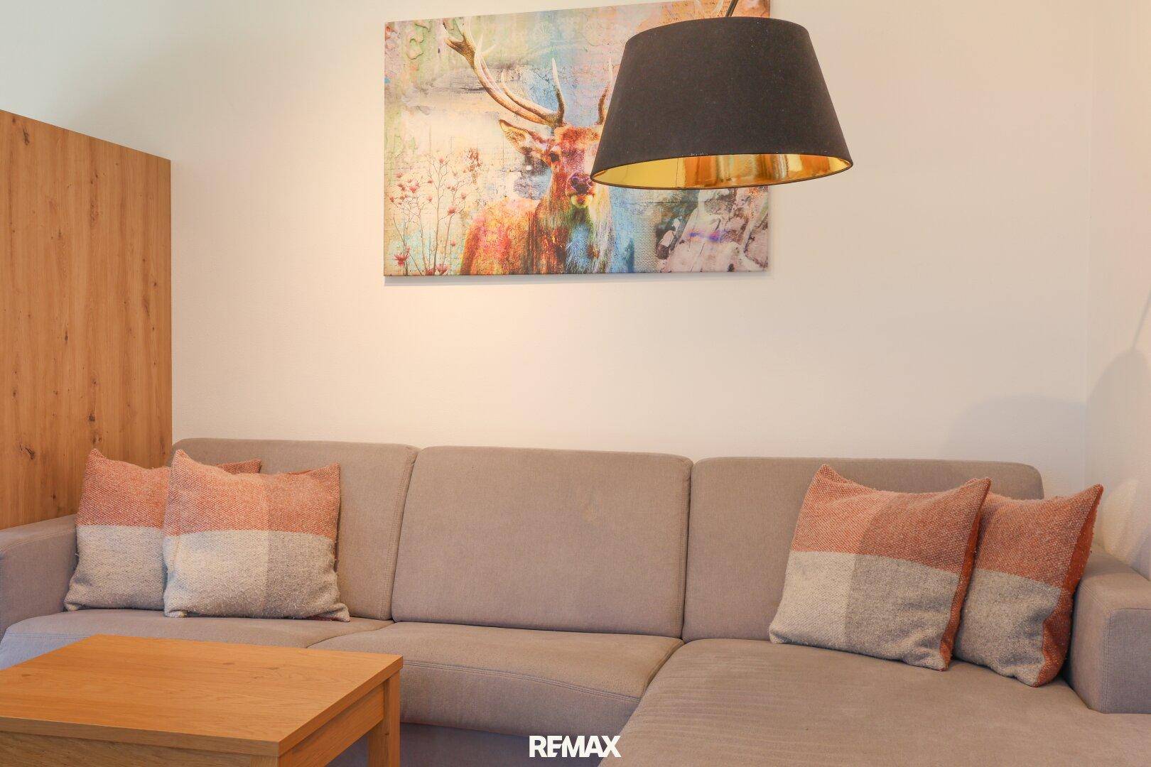 Gemütliches Sofa mit Kissen und einem modernen Bild an der Wand im Wohnbereich.