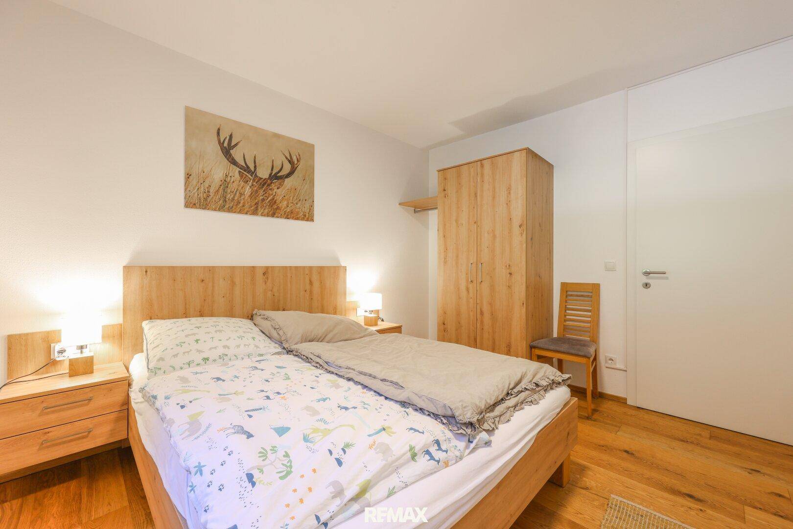 Schlafzimmer mit Doppelbett, Holzboden und einem Hirschbild an der Wand.