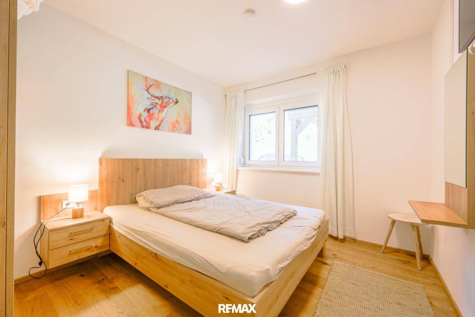 Gemütliches Schlafzimmer mit Holzbett, Nachttischen und einem Fenster für Tageslicht.