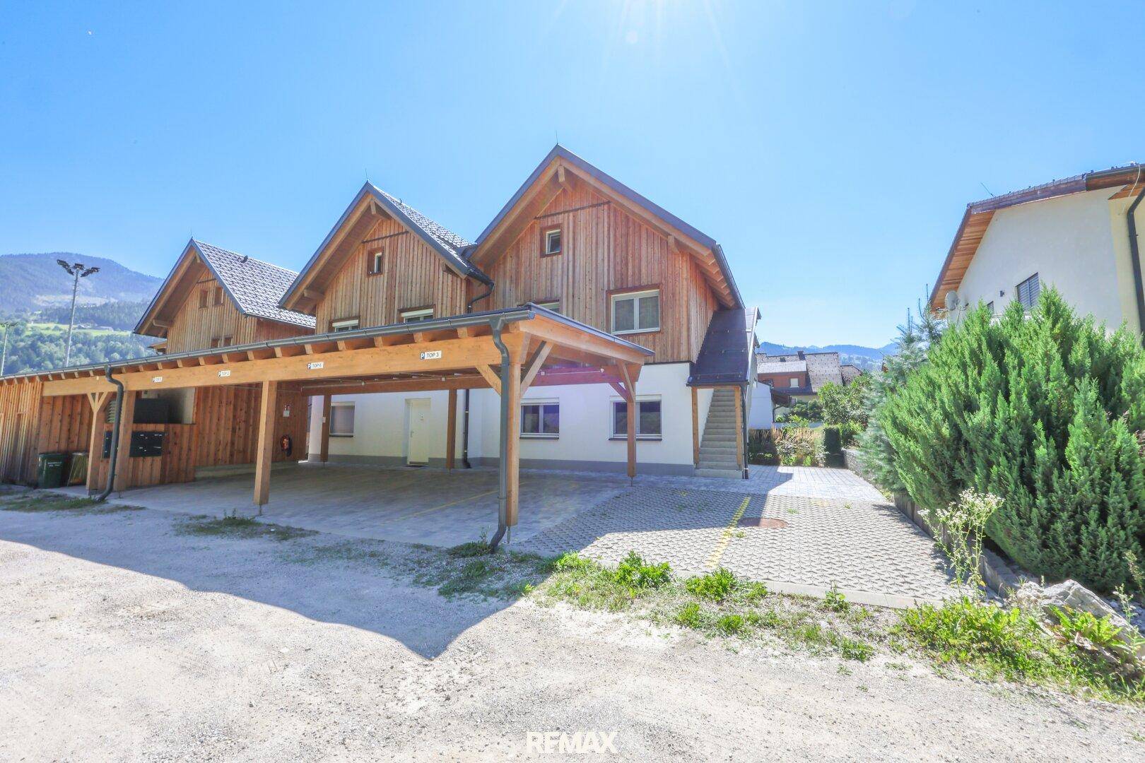 Rückansicht des Hauses mit Carport und Zufahrt, umgeben von ländlicher Umgebung.