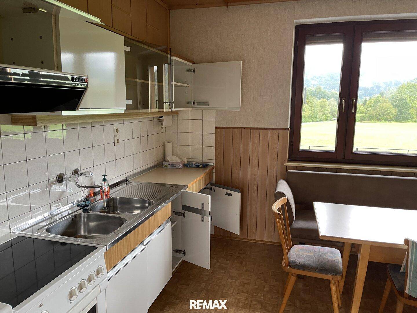 Funktionale Küche mit Einbauschränken, Essbereich und Fenster mit Blick ins Grüne.