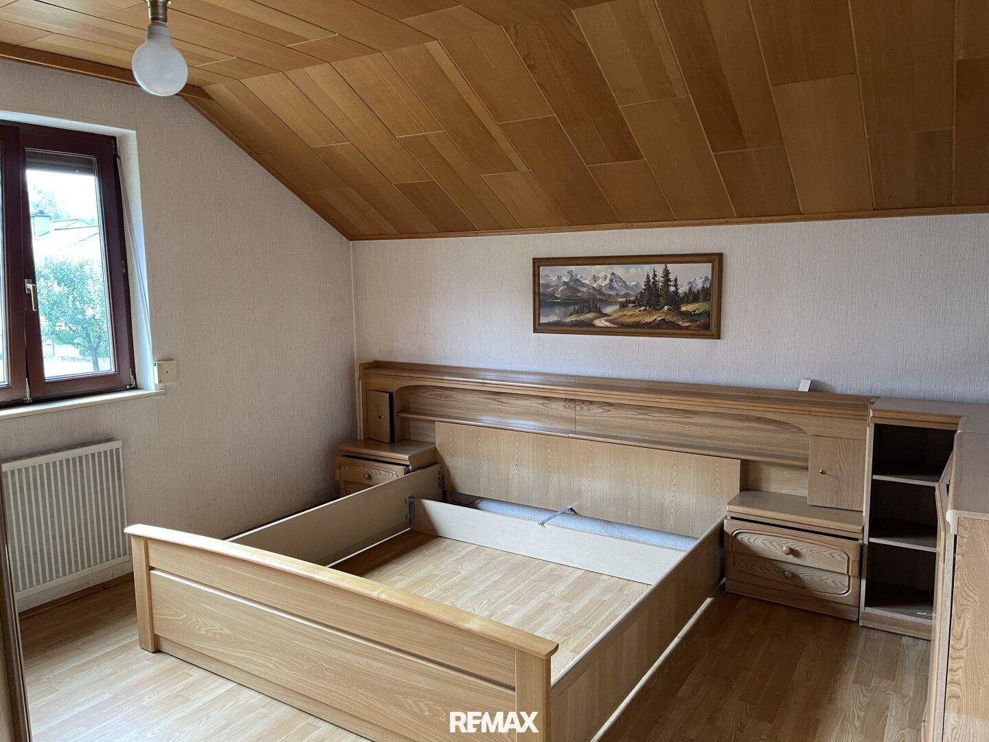 Schlafzimmer mit Holzbett, Holzdecke und Parkettboden, bietet eine gemütliche Atmosphäre.