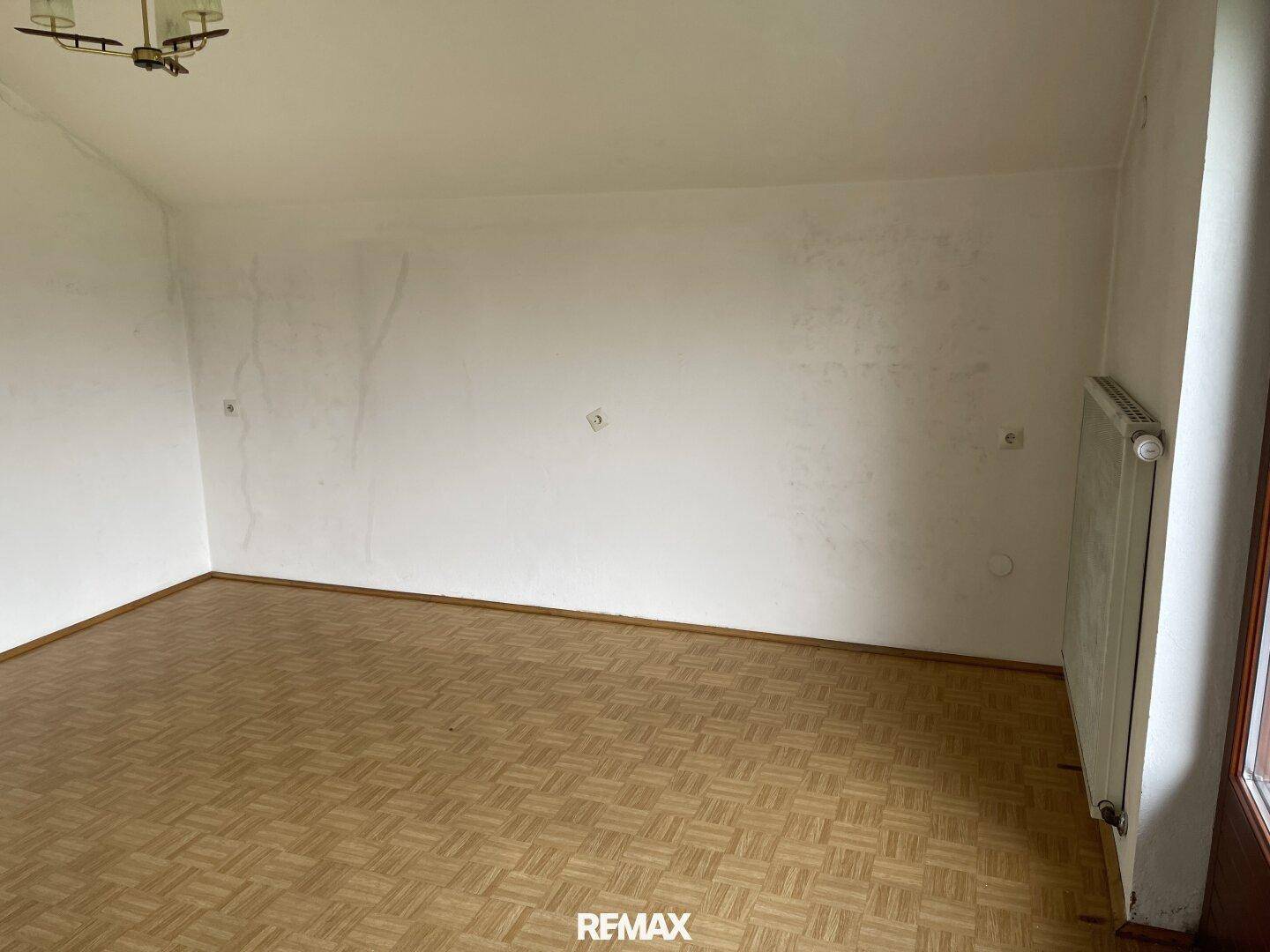 Geräumiges Wohnzimmer mit Parkettboden und hellen Wänden, bereit zur individuellen Gestaltung.
