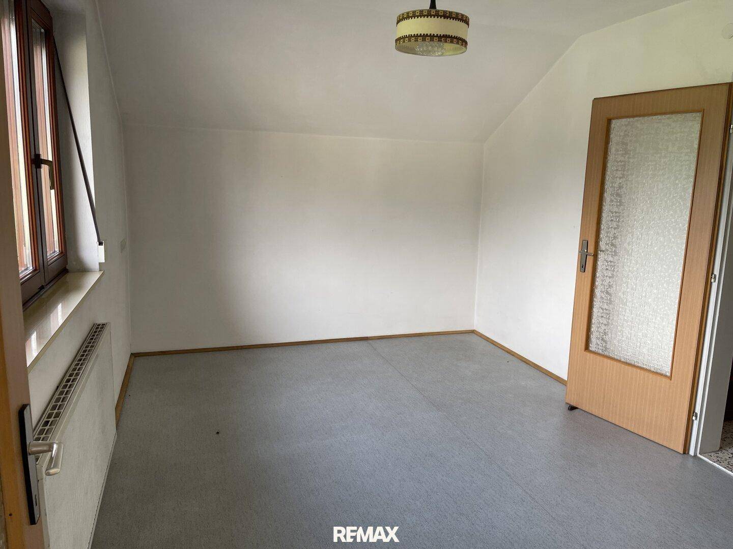 Helles Schlafzimmer mit Teppichboden, Dachschräge und Fenster, ideal für ein Kinderzimmer.