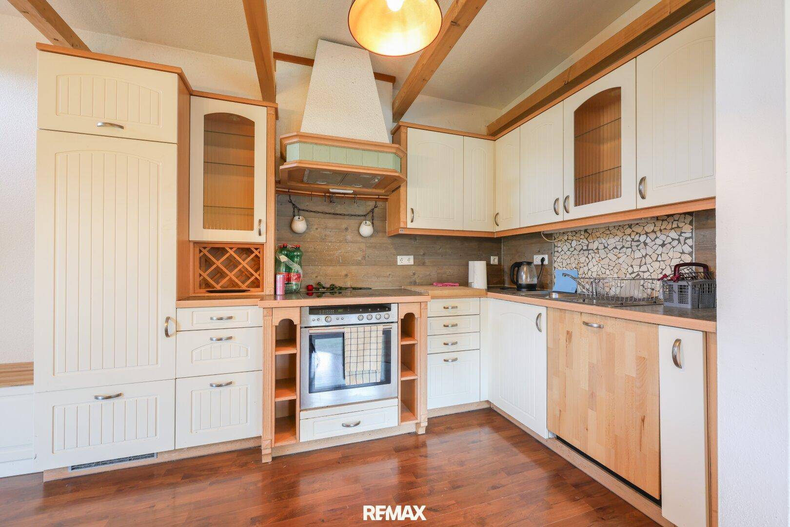 Traditionelle Küche mit hellen Holzschränken, Backofen und dekorativem Fliesenspiegel.