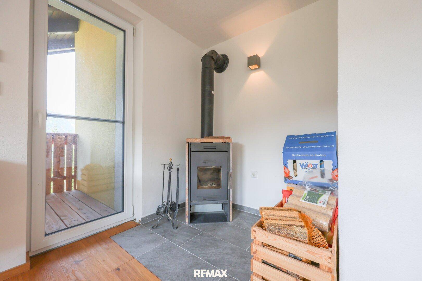 Detailansicht des Kaminofens mit Holzscheiten und Zugang zur Terrasse oder Balkon.