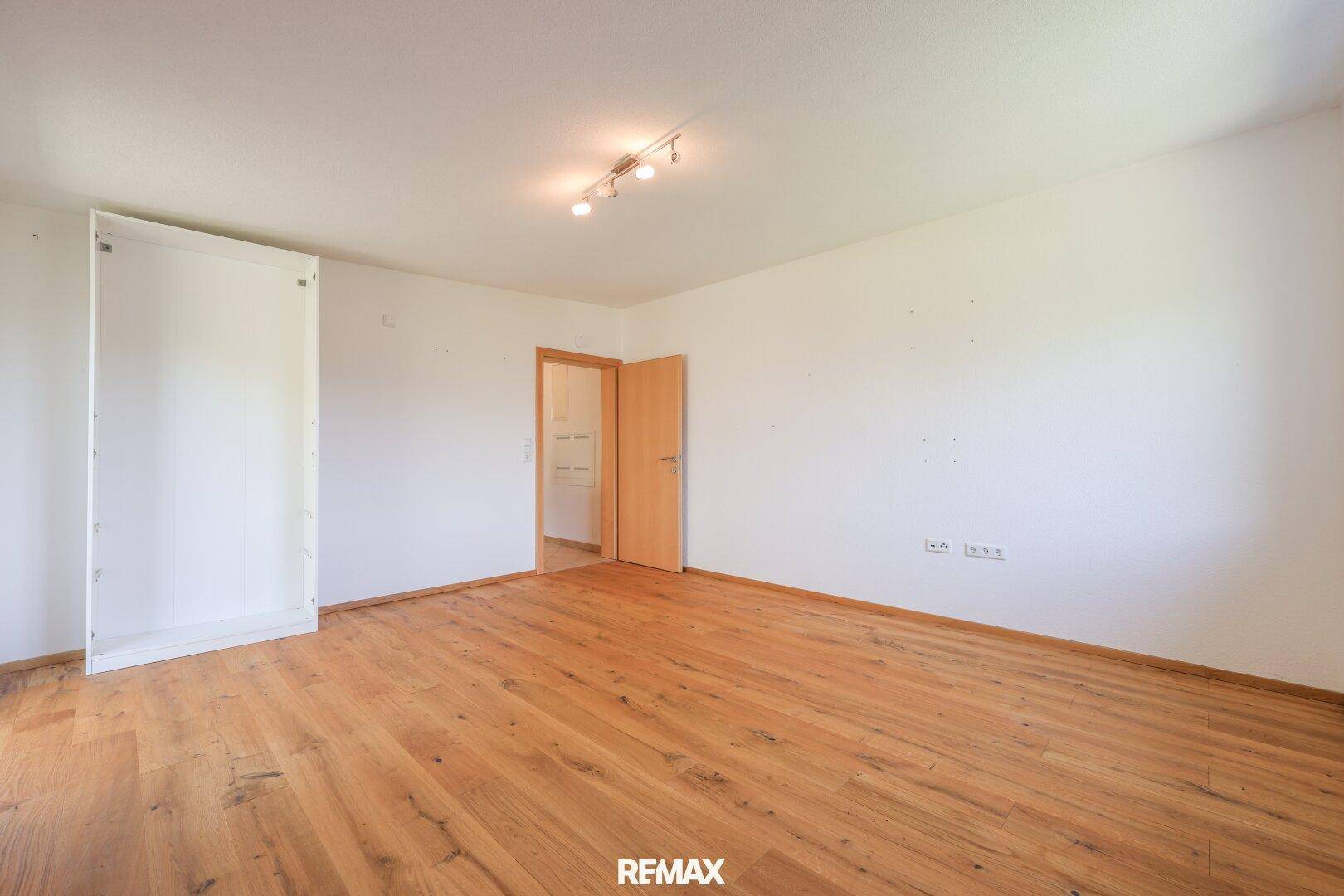 Helles Zimmer mit Holzboden und weiß gestrichenen Wänden, bereit zur individuellen Gestaltung.