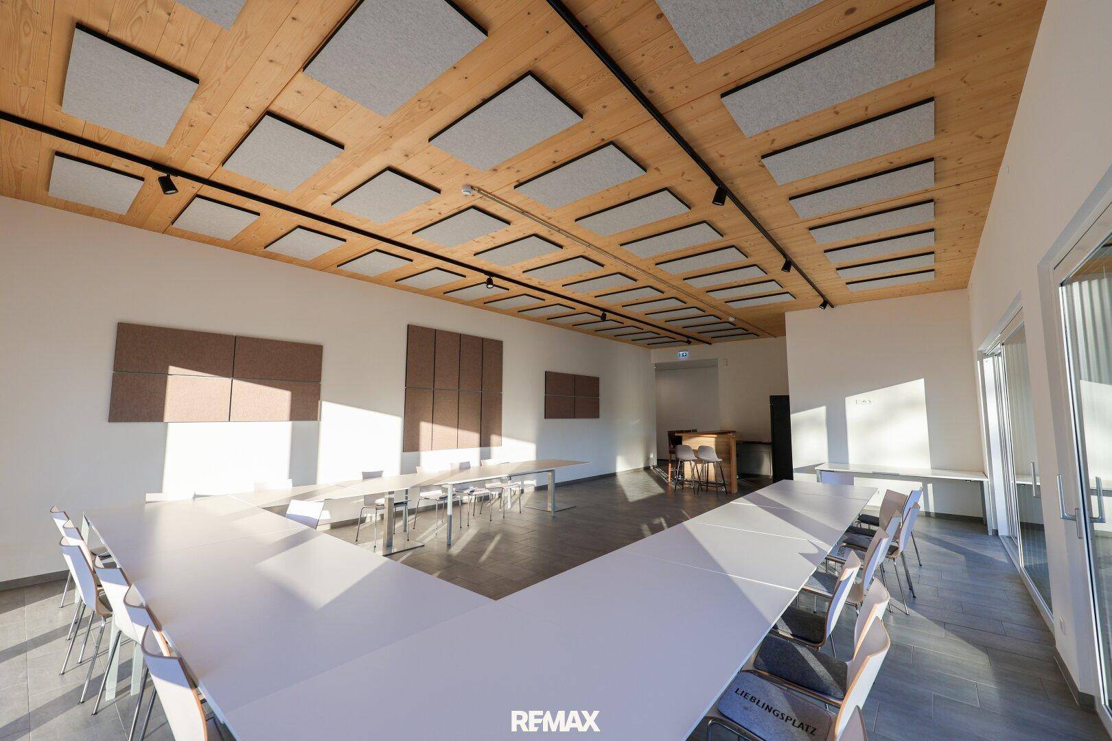 Großer, heller Konferenzraum mit Holzbalkendecke und Schallschutzplatten, bereit für Veranstaltungen.