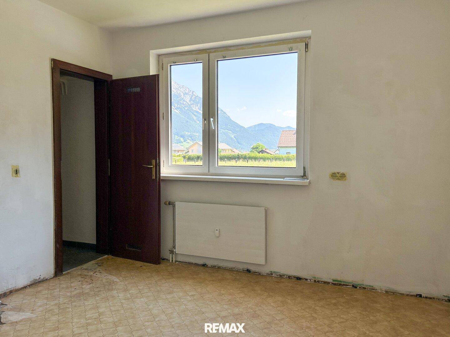 Schlafzimmer mit Bergblick und älterem Bodenbelag, bereit für eine Renovierung.