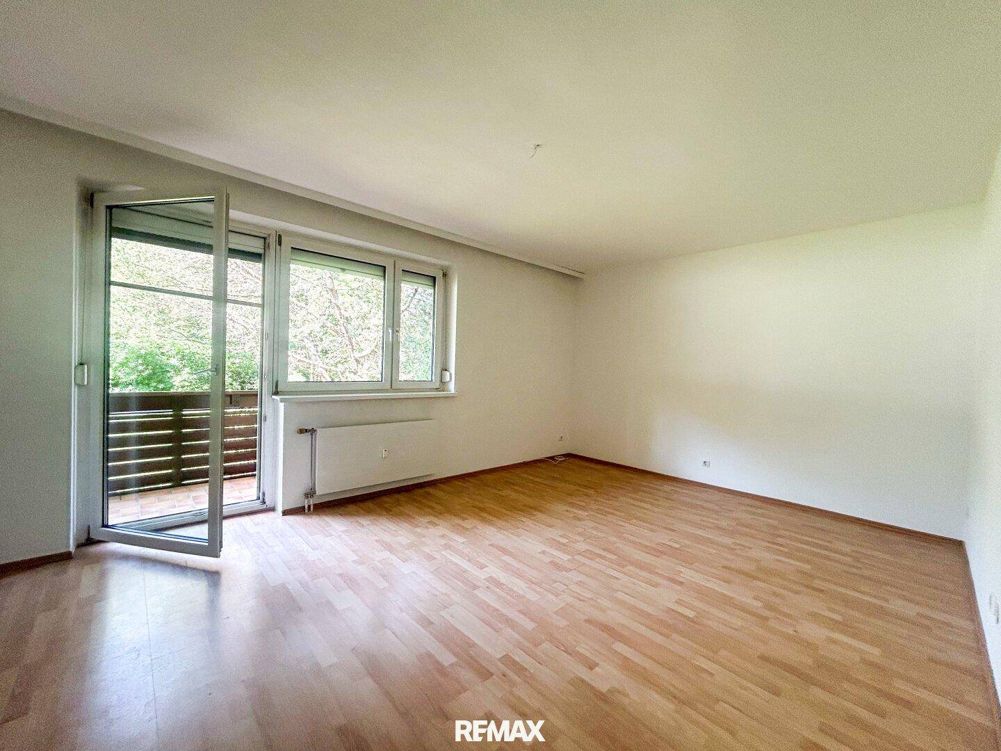 Geräumiges Zimmer mit Laminatboden und Zugang zu einem Balkon, bietet viel Tageslicht.