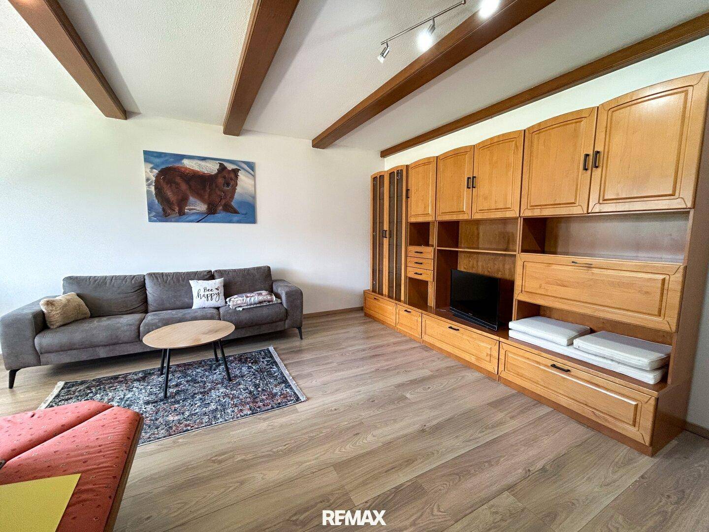 Wohnzimmer mit Holzbalkendecke, Laminatboden und traditionellen Holzschränken.