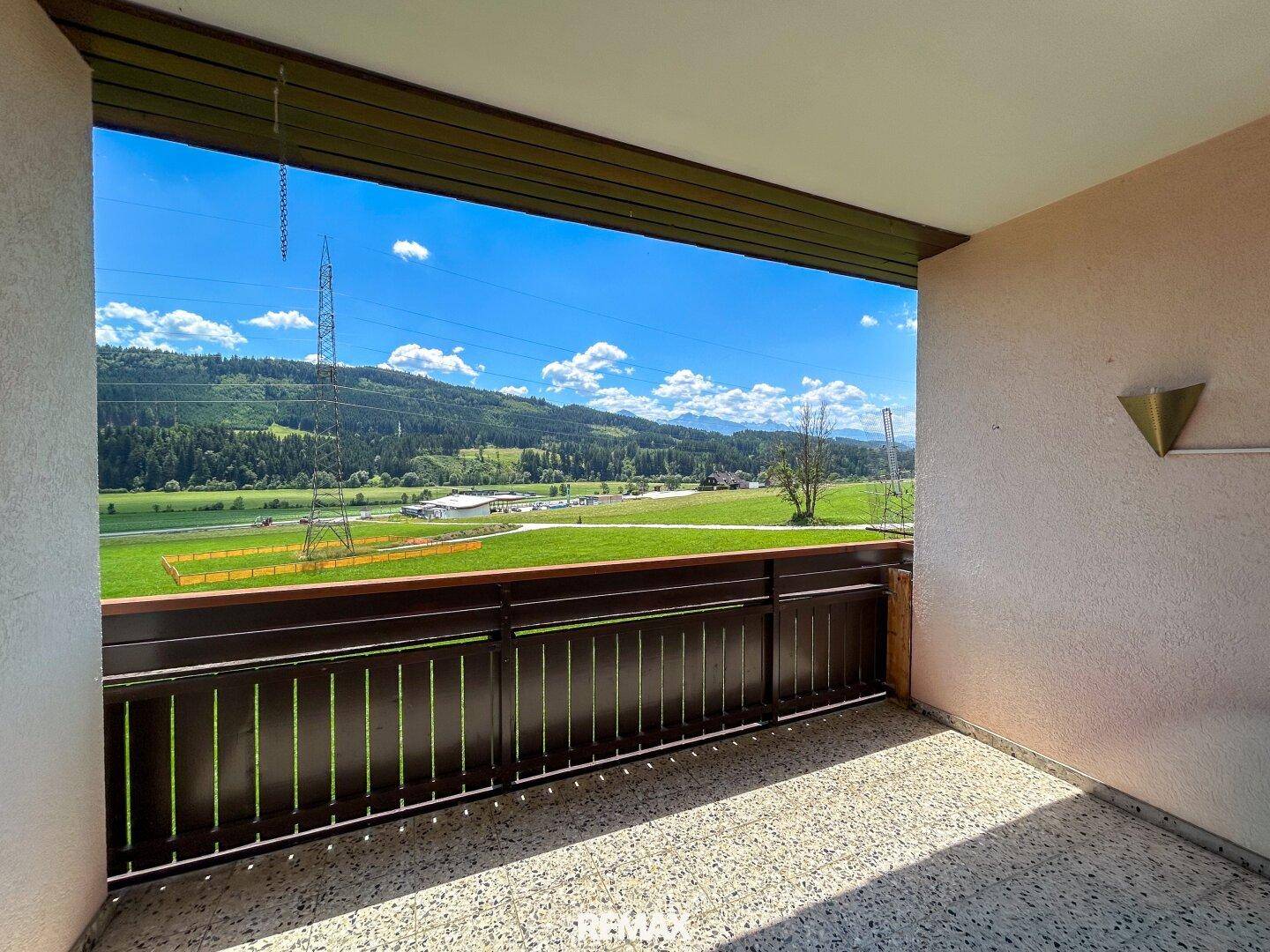 Geräumiger Balkon mit weitem Blick über grüne Wiesen und Berge.