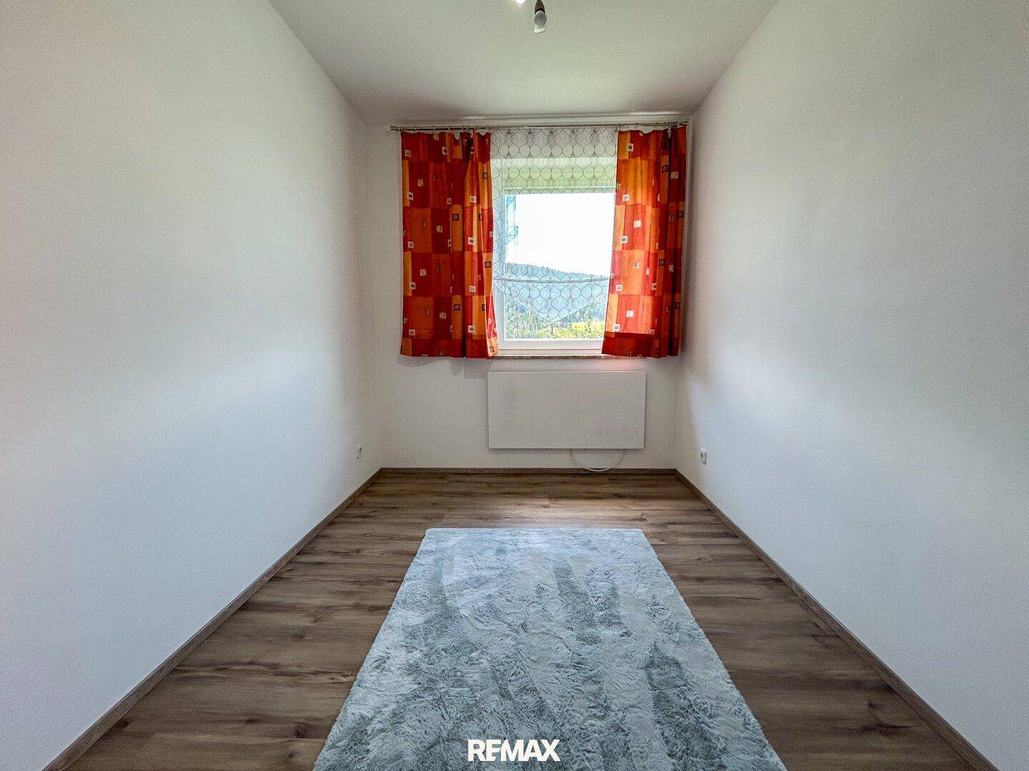 Helles Zimmer mit Laminatboden und Fenster, ideal als Kinder- oder Gästezimmer.