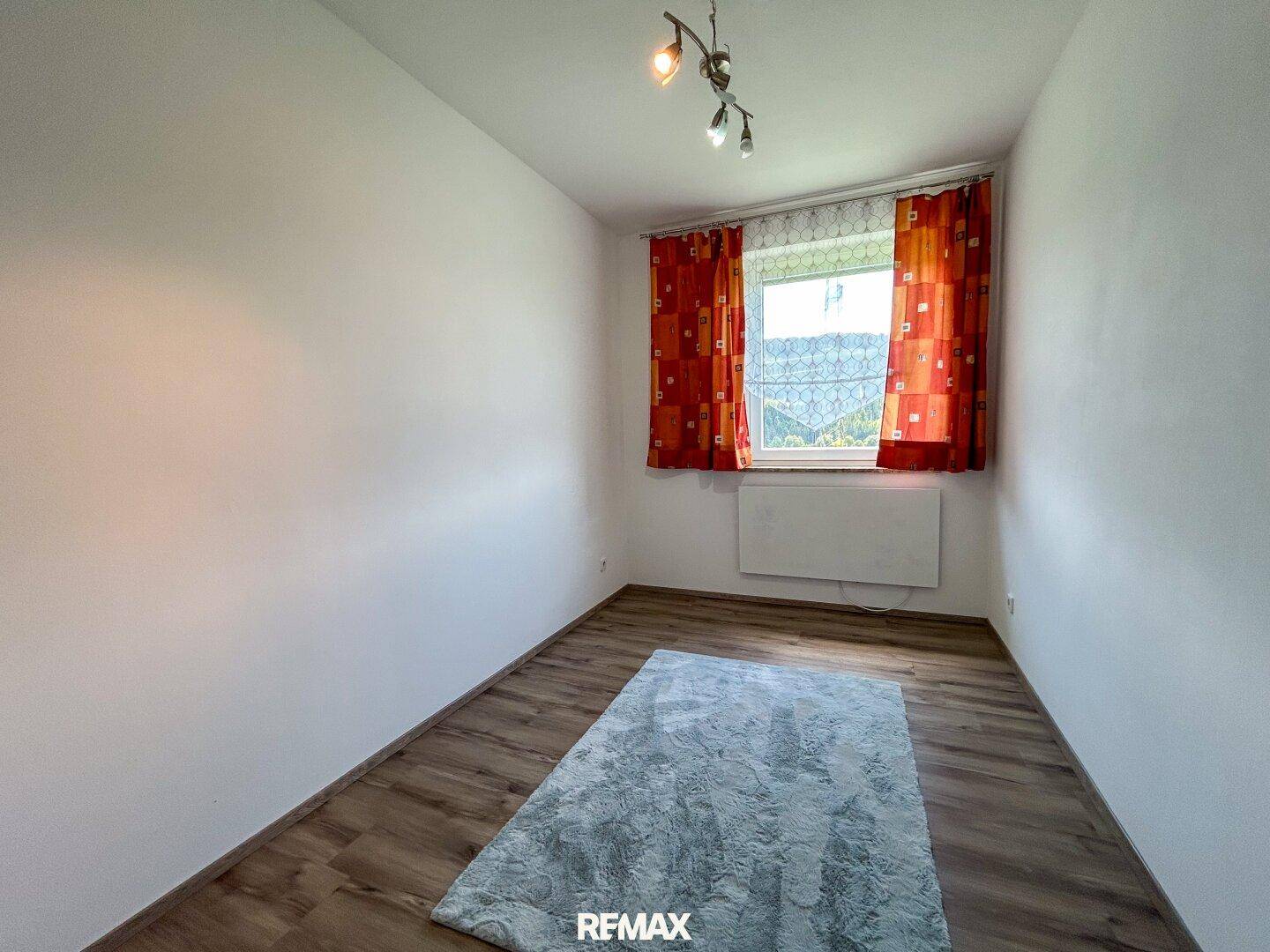 Kleines Schlafzimmer oder Kinderzimmer mit Laminatboden und Fenster.
