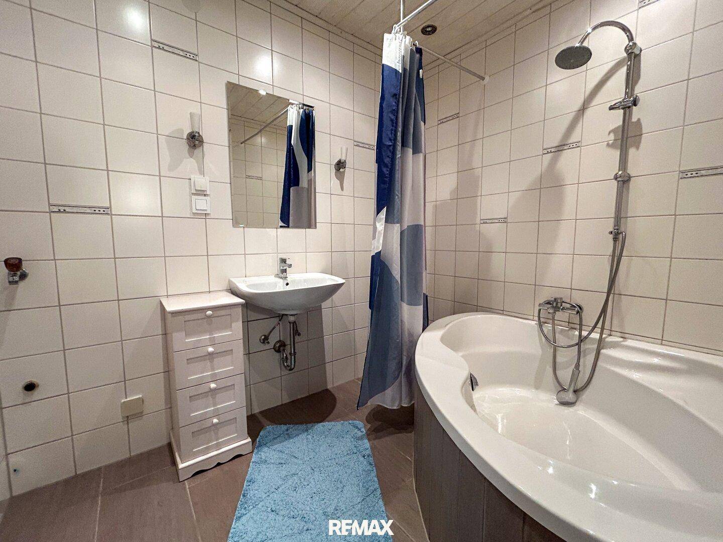 Badezimmer mit Eckbadewanne, Dusche und weißen Fliesen.