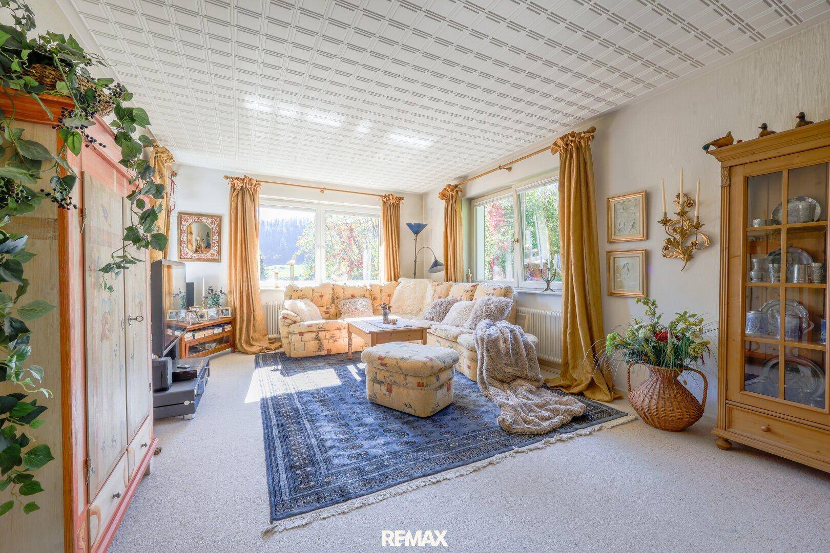 Helles Wohnzimmer mit Teppichboden, bequemer Couch und traditionellen Holzmöbeln.
