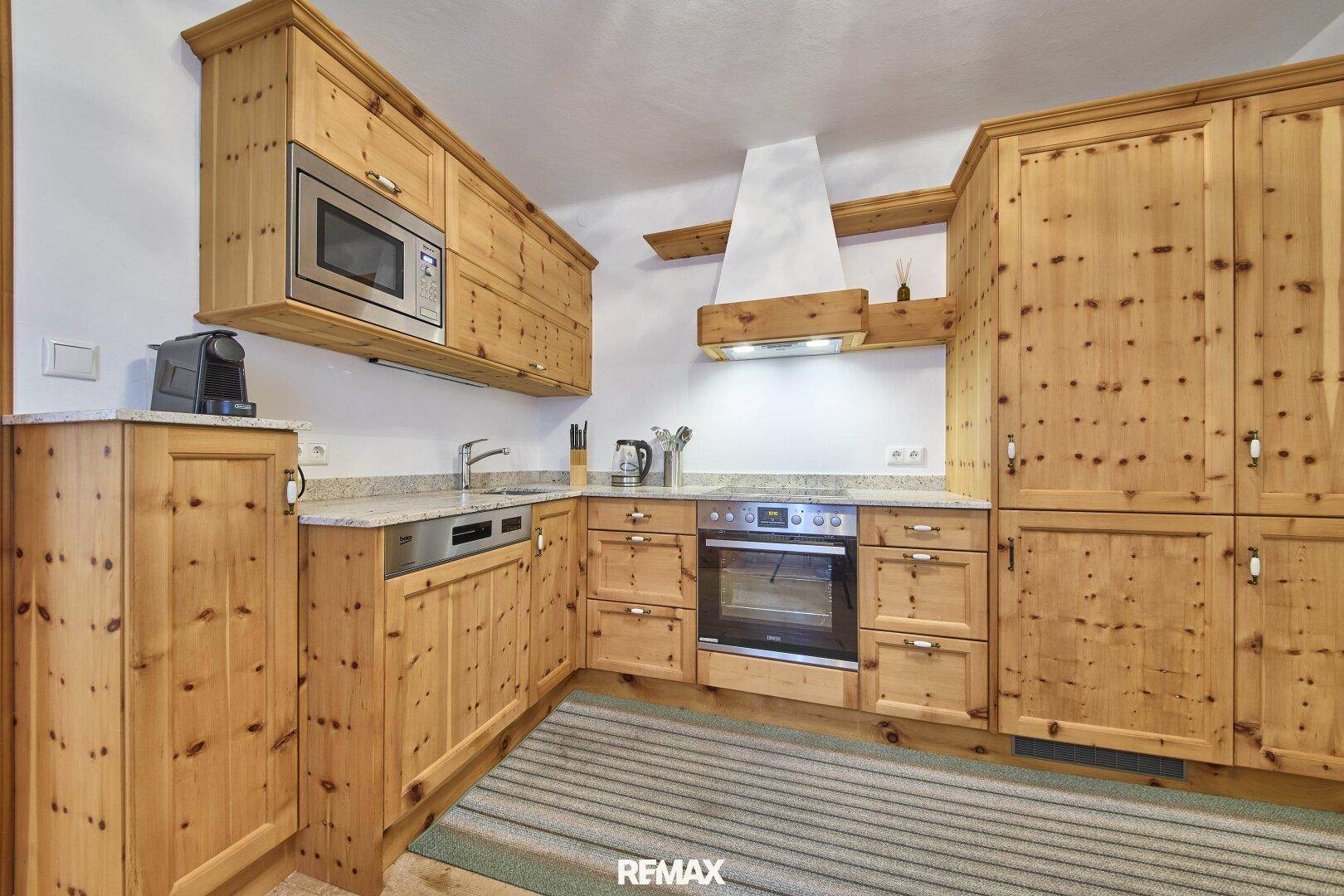 Voll ausgestattete Holzküche im Landhausstil mit modernen Einbaugeräten und Granitarbeitsplatten.