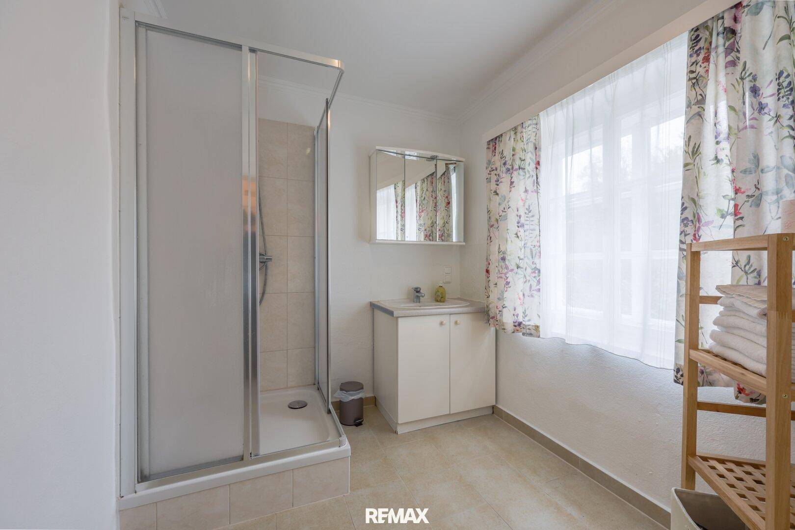 Funktionales Badezimmer mit Duschkabine, Waschbecken und Fenster für Tageslicht.