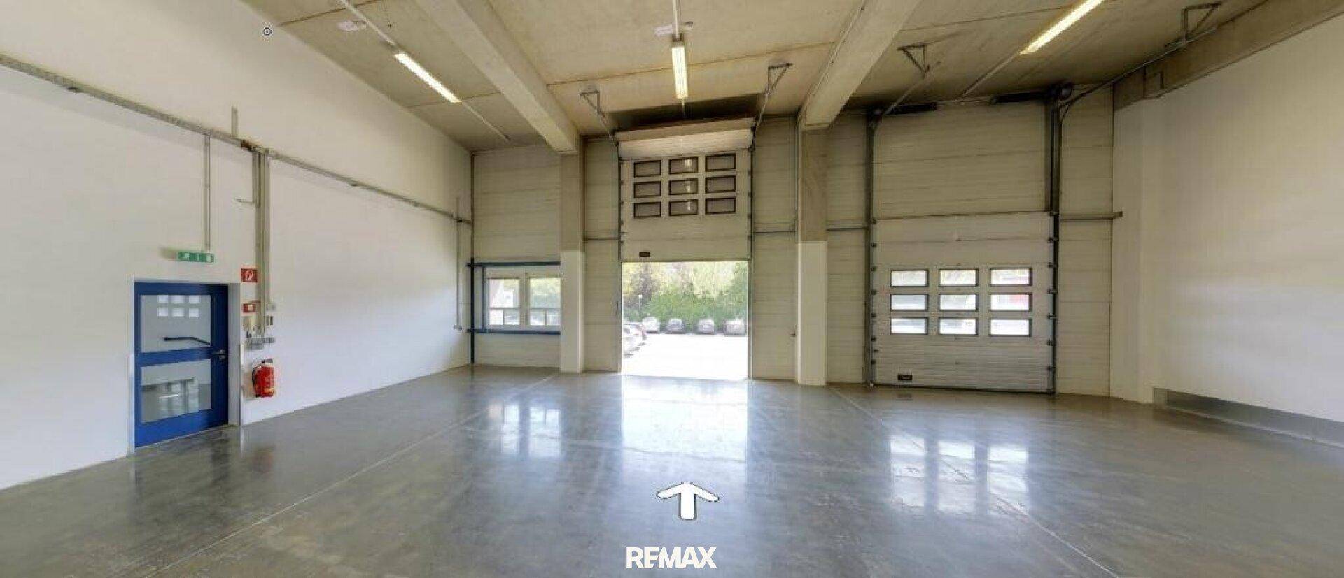Geräumige Lagerhalle mit Betonboden, hohen Decken und großen Rolltoren für den Zugang.