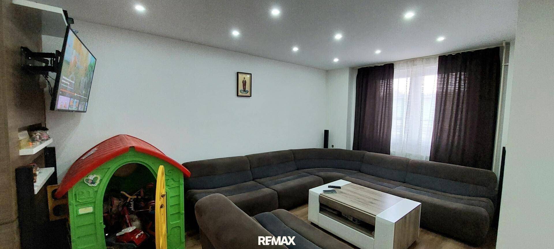 Gemütliches Wohnzimmer mit großem Ecksofa, Fernseher und Spielbereich für Kinder.