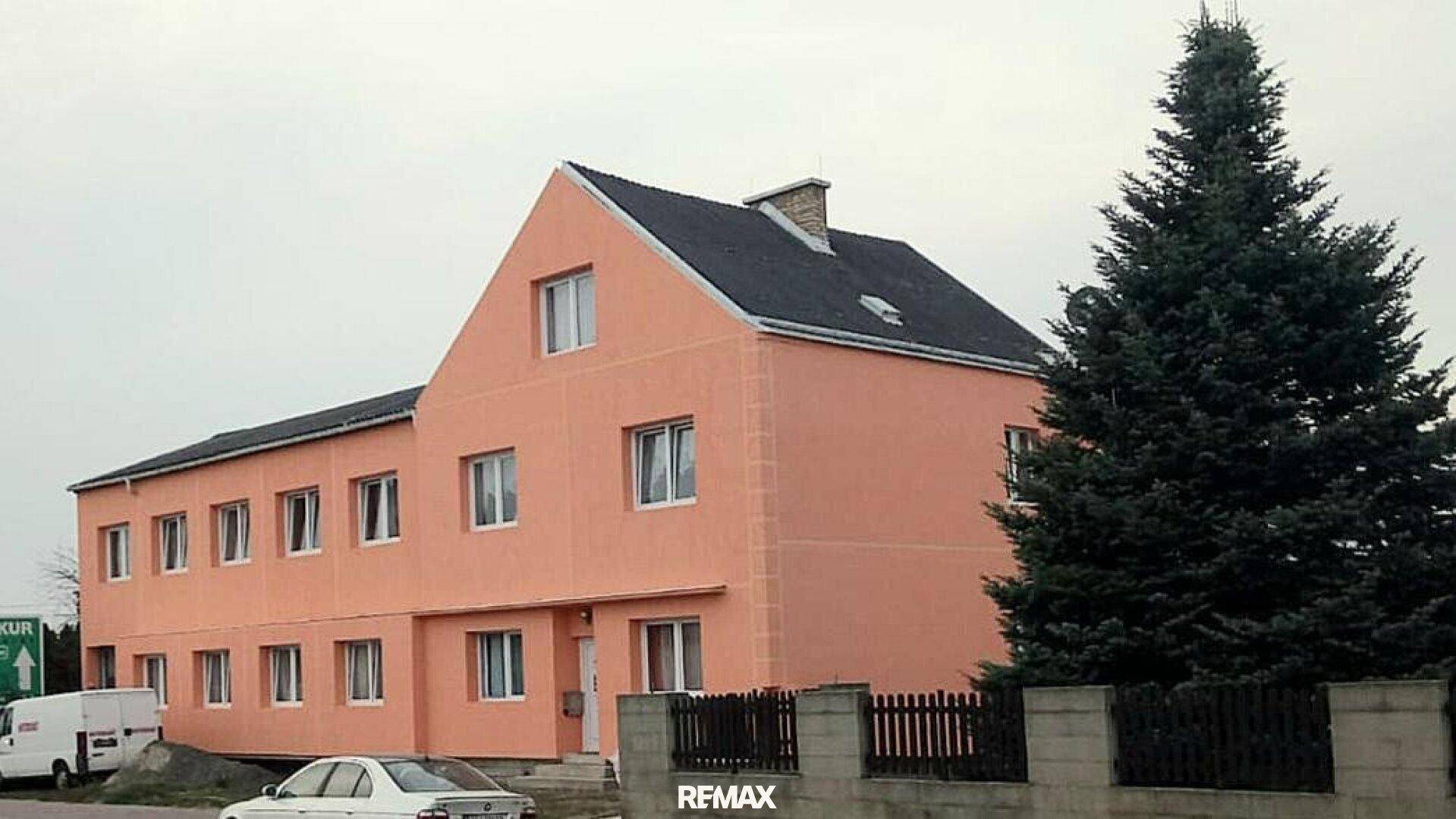 Mehrstöckiges Wohngebäude mit auffälliger orangefarbener Fassade und klassischem Satteldach.