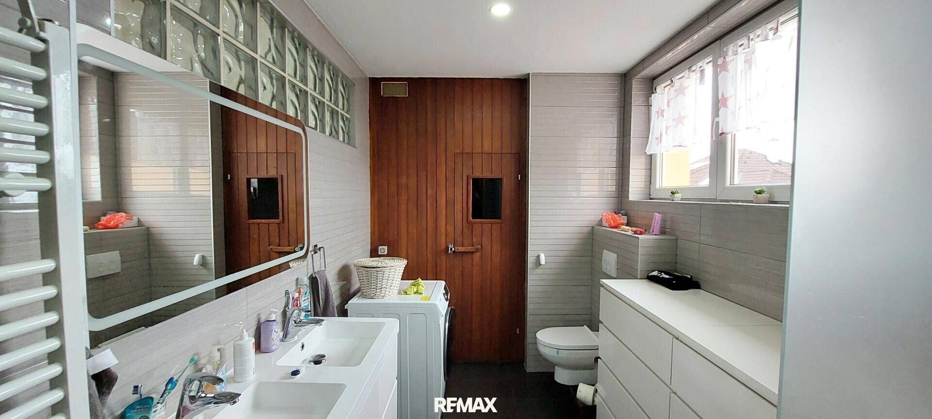 Badezimmer mit Doppelwaschbecken, beheiztem Handtuchhalter und Glasbausteinen.