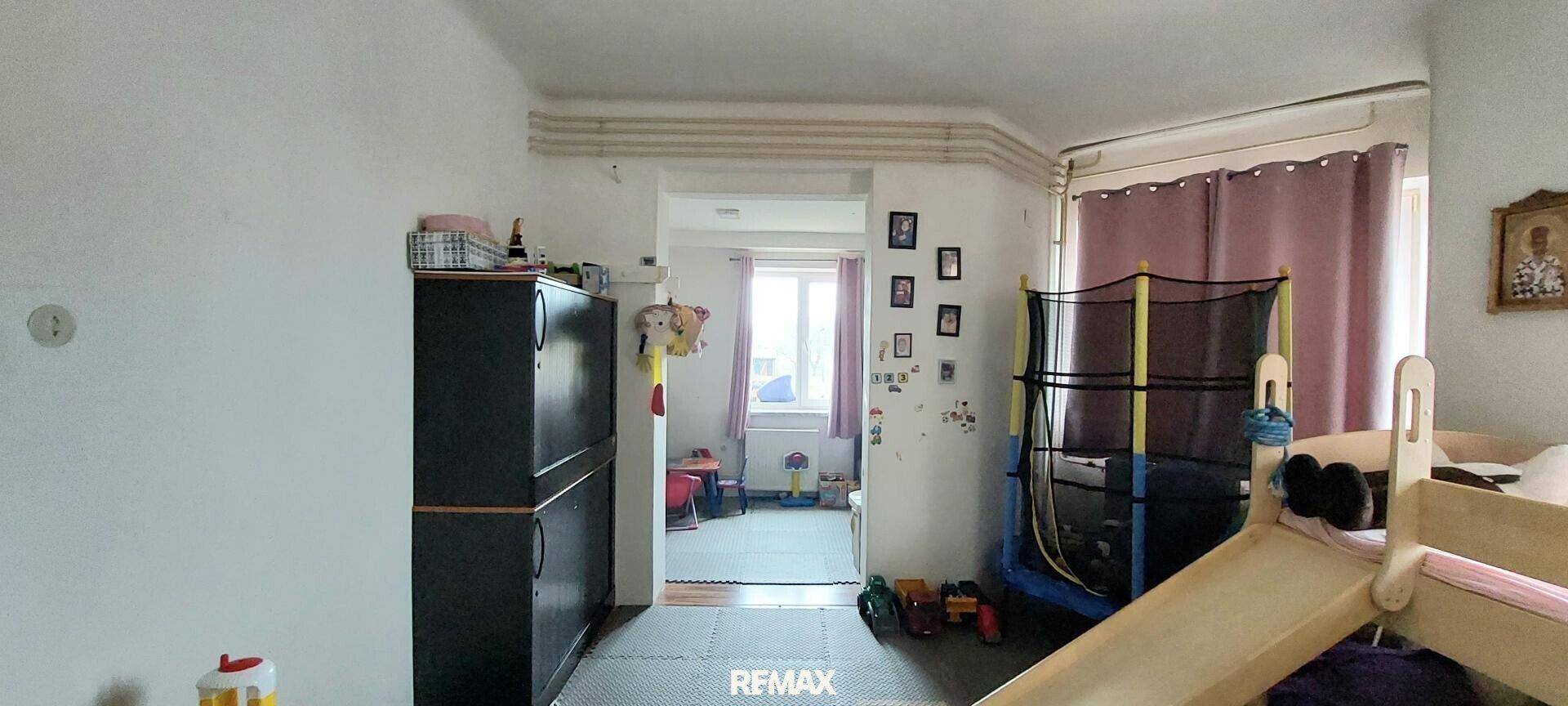 Helles Kinderzimmer mit Spielgeräten, Trampolin und Rutsche, ideal zum Spielen.