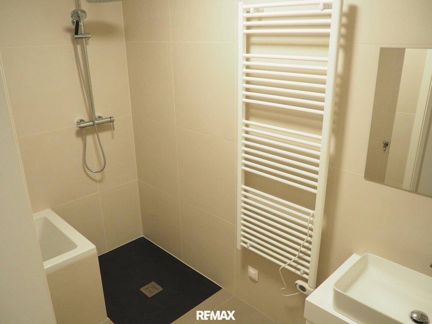 Modernes Badezimmer mit Dusche, beheiztem Handtuchhalter und stilvollem Waschbecken.