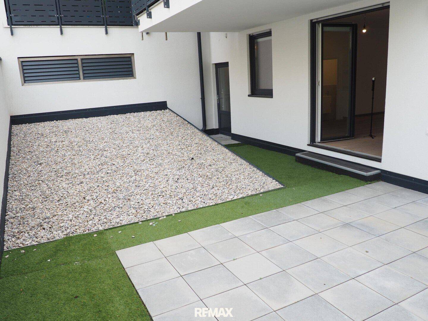 Weitläufige Terrasse mit Kiesbeet und Kunstrasenfläche, bietet viel Platz für individuelle Gestaltung.