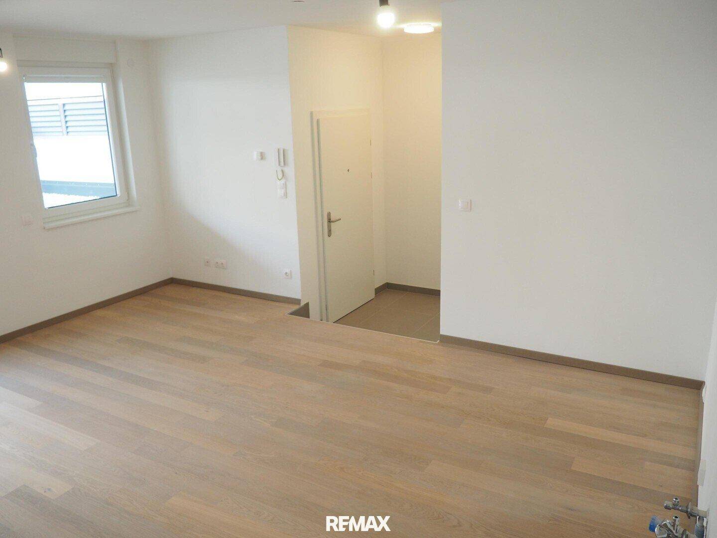 Heller Wohnbereich mit Holzboden und Fenster, bietet einen einladenden Eingangsbereich.