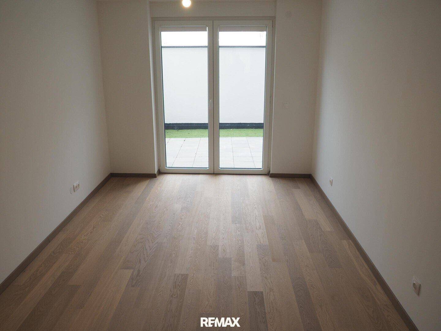 Helles Schlafzimmer mit Holzboden und Zugang zu einem Außenbereich, ideal für Ruhe.