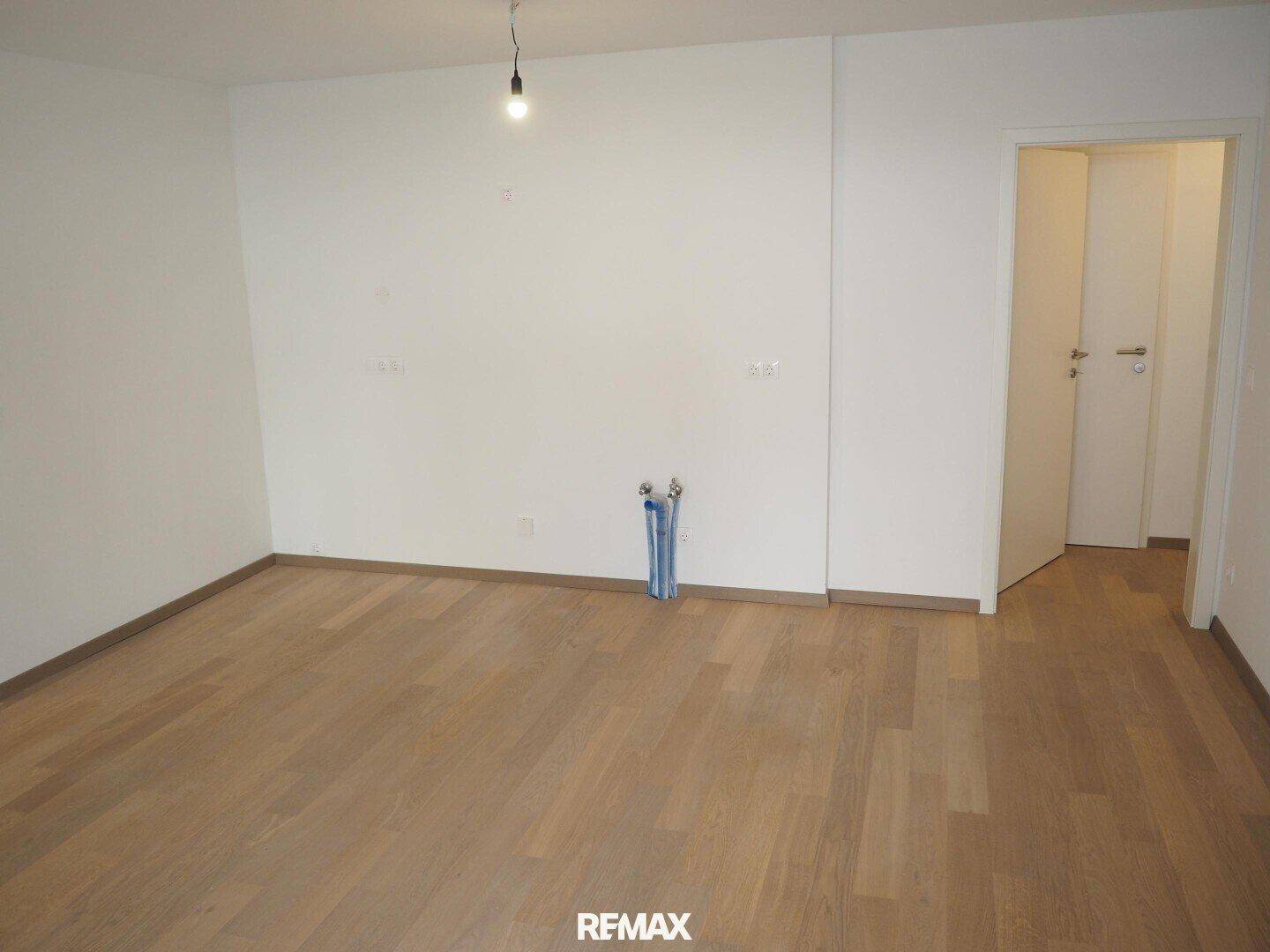 Leerer Raum mit Holzboden und vorbereiteten Anschlüssen, bietet flexible Nutzungsmöglichkeiten.