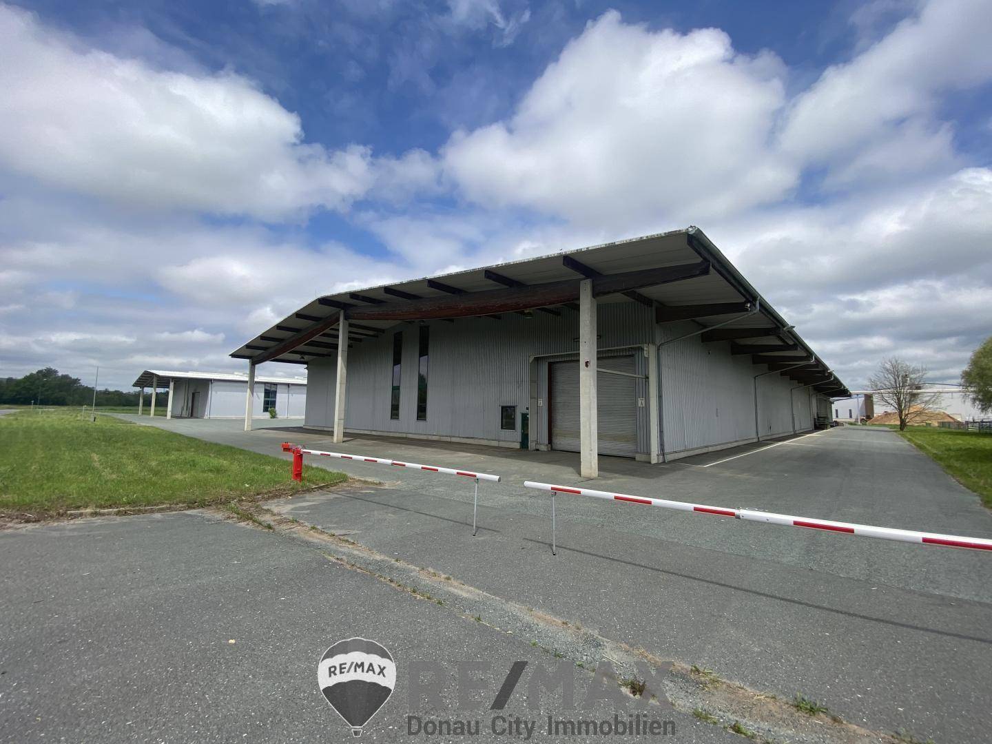 Ansicht der modernen Lagerhalle mit Zufahrt und Absperrung unter einem weitläufigen Vordach.