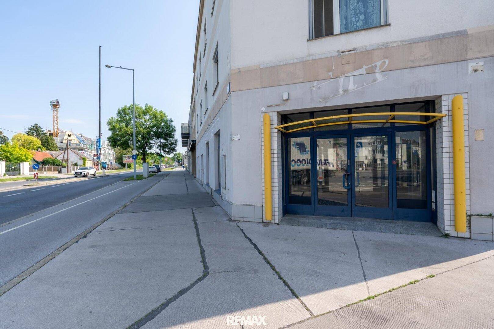 Außenansicht des Gebäudes von der Straße mit dem Haupteingang und umliegender Infrastruktur.