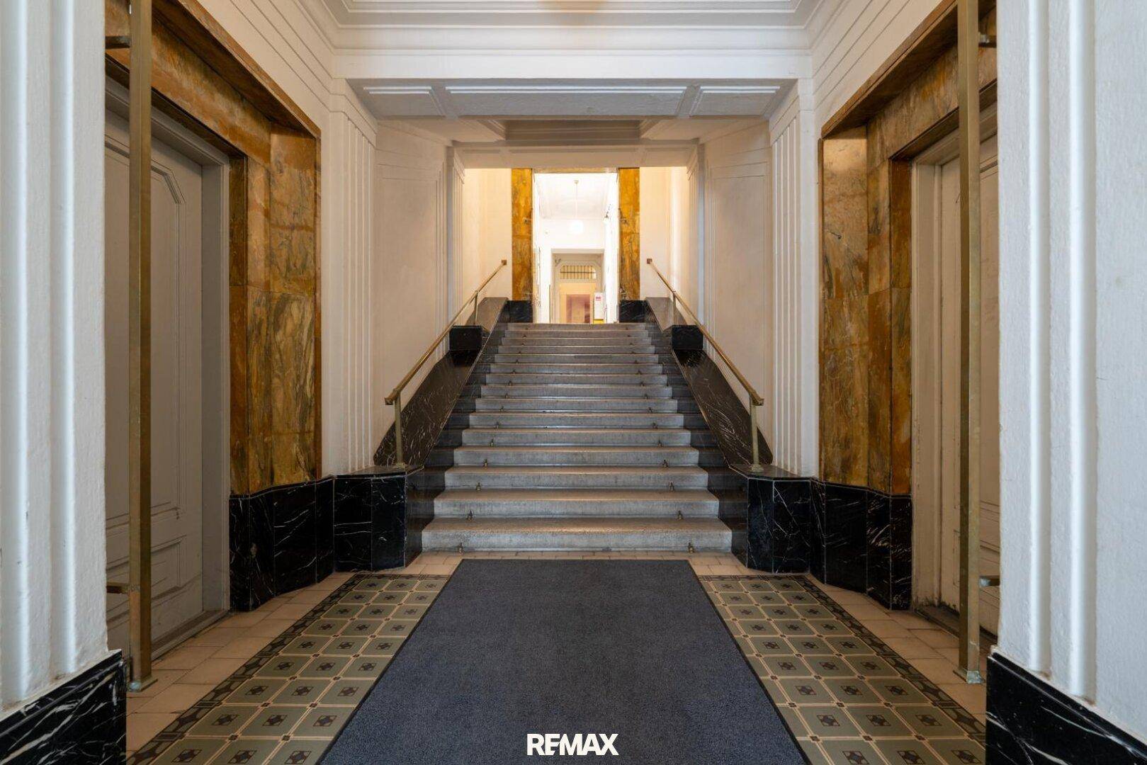 Großzügiges Treppenhaus mit Marmorverkleidung und eleganten Säulen im Altbau.