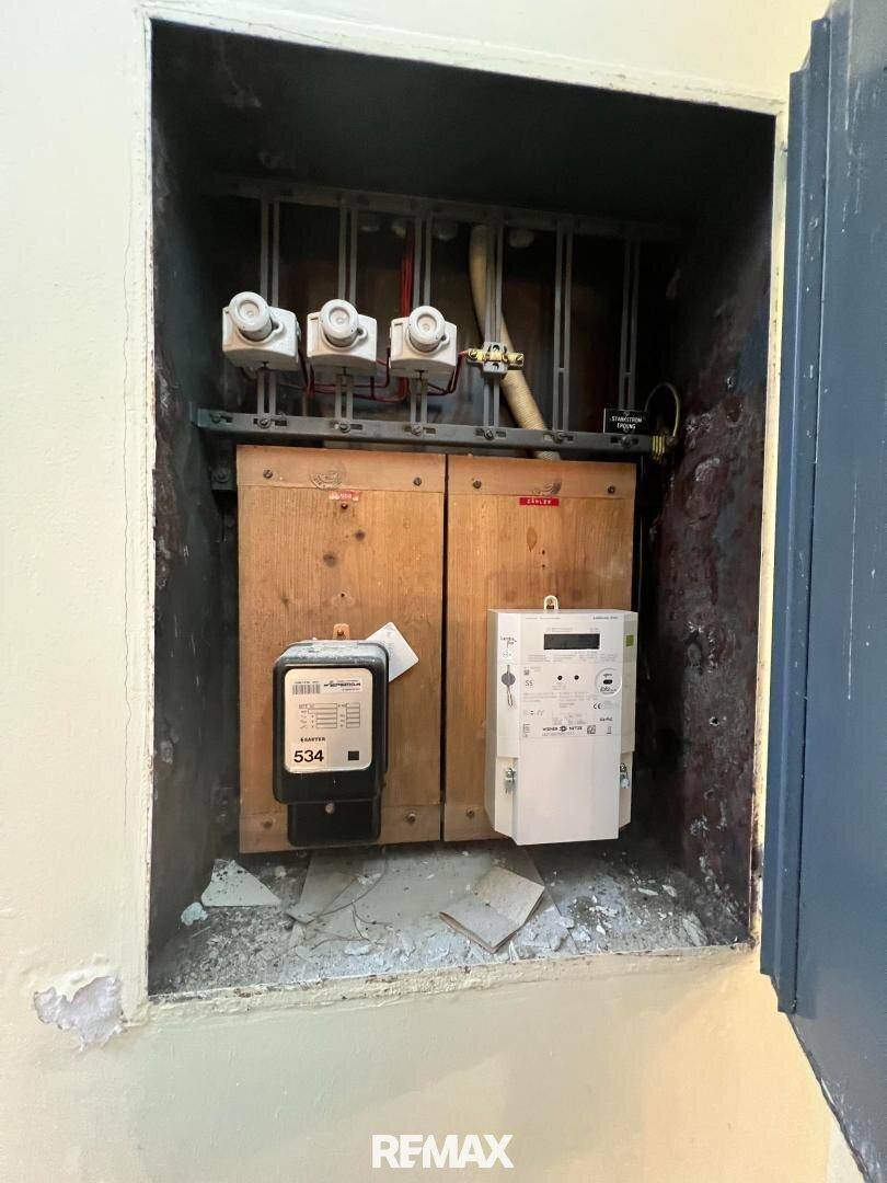 Nahaufnahme von Stromzählern und elektrischen Installationen in einem geöffneten Schaltschrank.