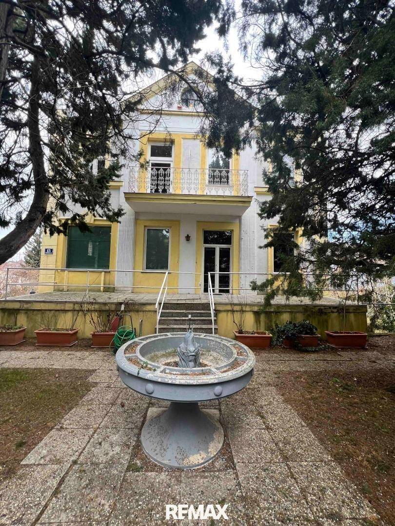 Vorderansicht der Villa mit einer Treppe zum Eingang und einem dekorativen Brunnen im Vorgarten.