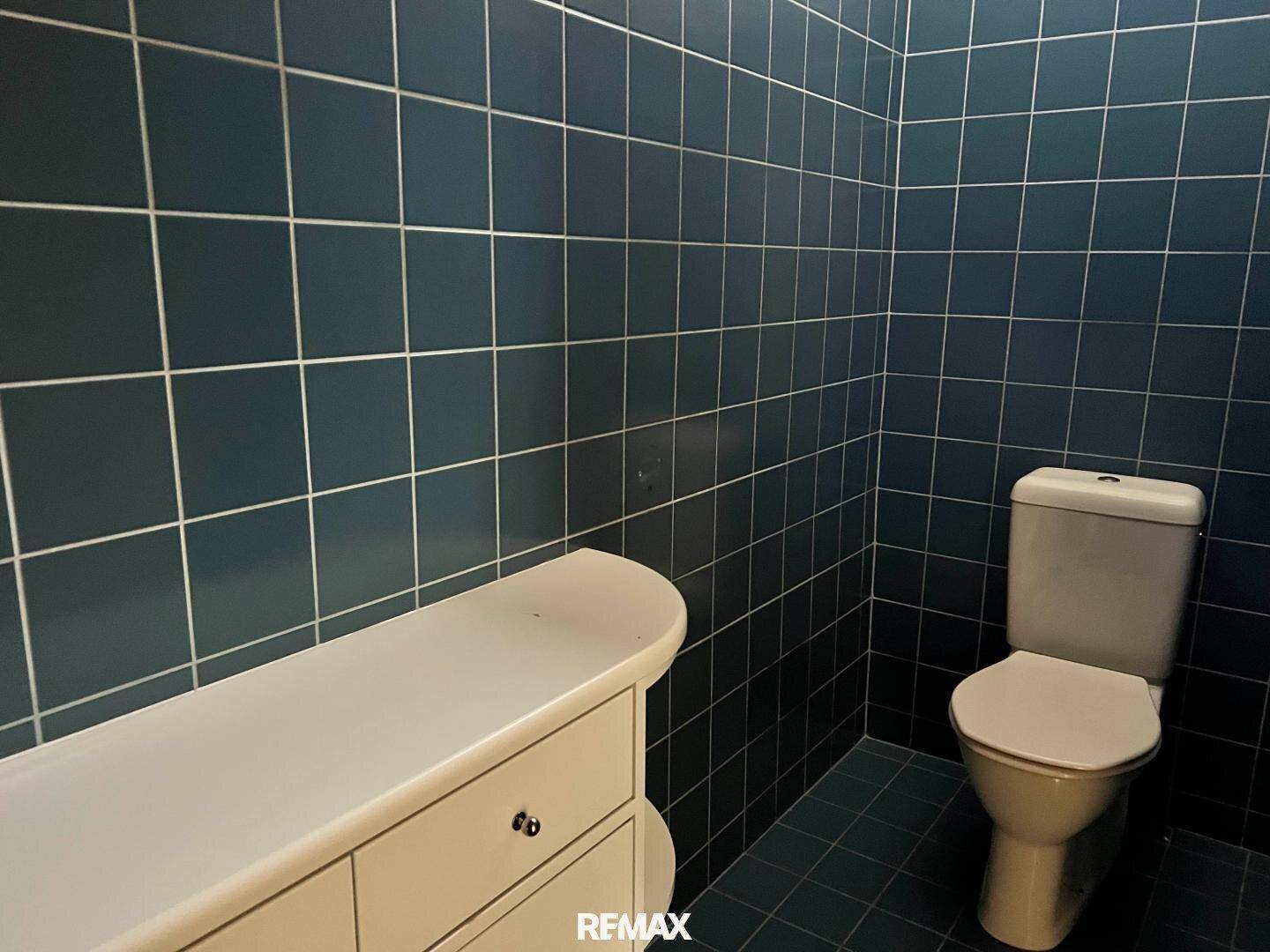 Separate Toilette mit blauen Wand- und Bodenfliesen und einem einfachen WC.