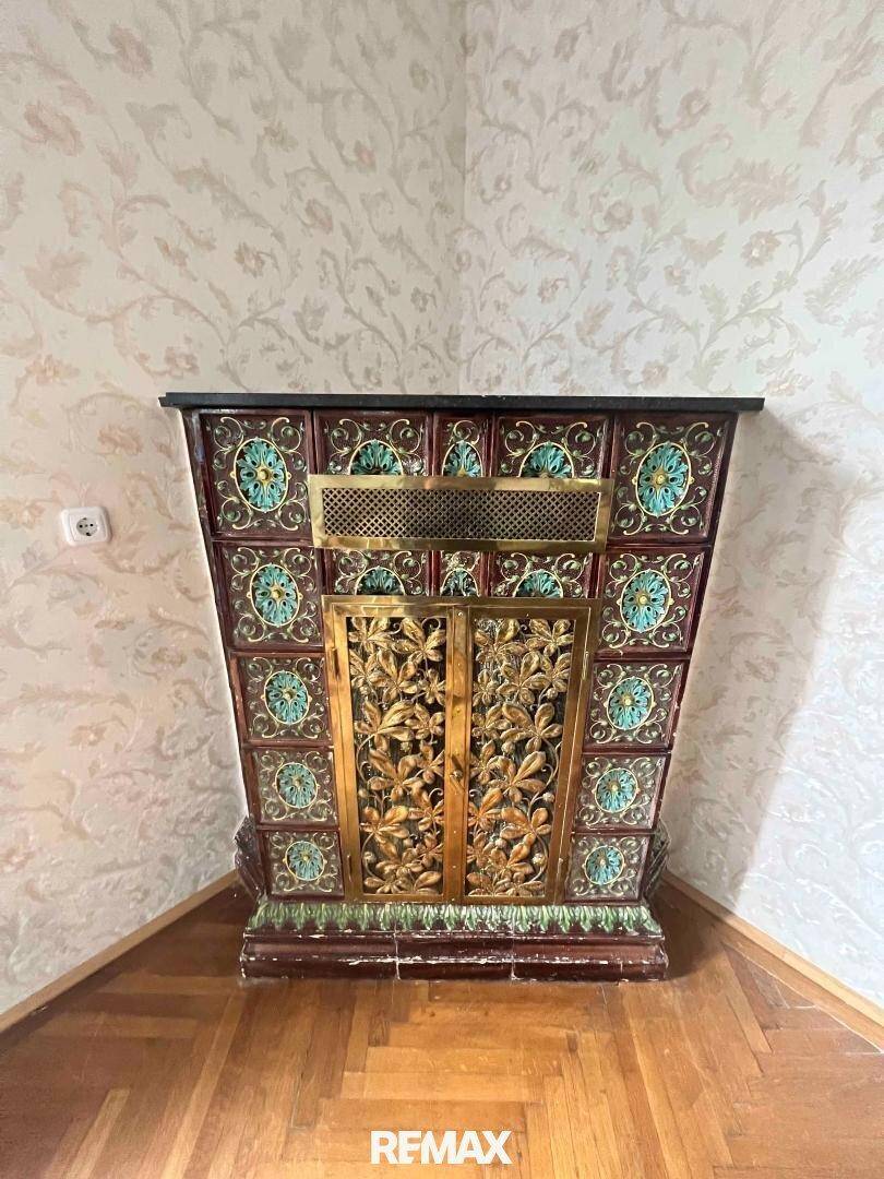 Detailansicht eines kunstvoll verzierten Kachelofens mit floralen Mustern in einer Ecke des Raumes.