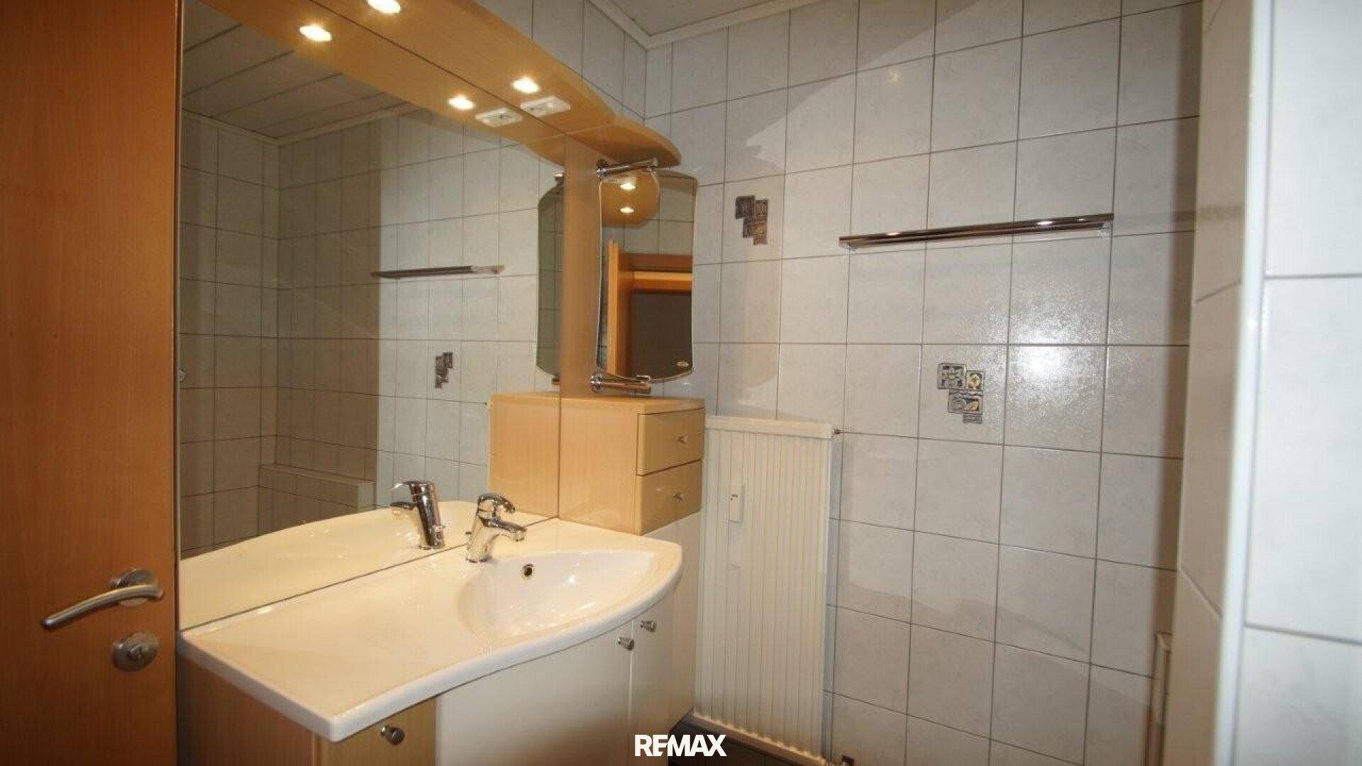 Badezimmer mit modernem Waschbecken, großem Spiegel und Spiegelschrank.
