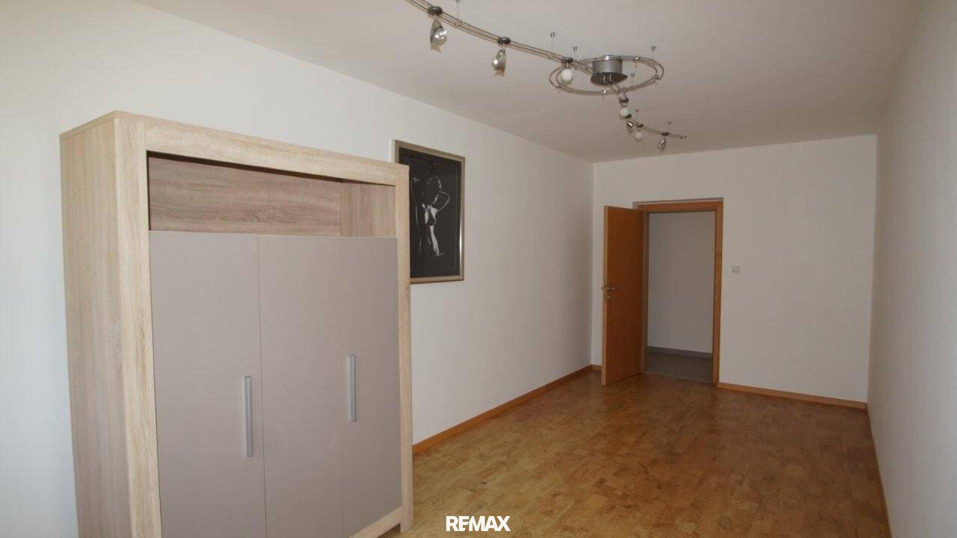 Heller Raum mit Holzfußboden, einem Kleiderschrank und einer Tür, vielseitig nutzbar.