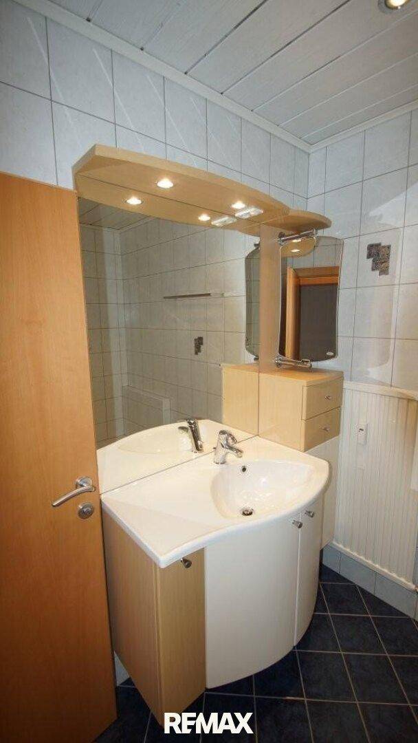 Badezimmer mit modernem Waschbecken, großem Spiegel und Spiegelschrank.
