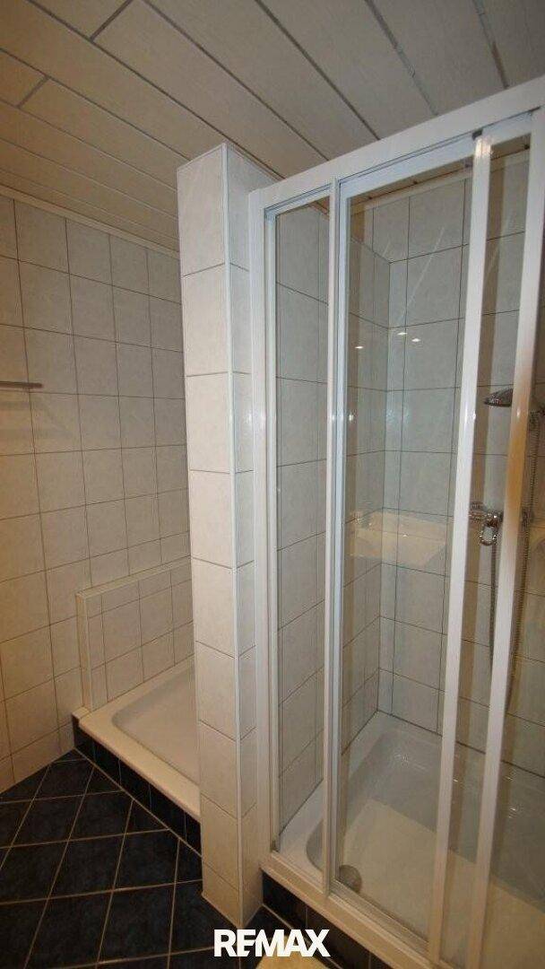 Duschkabine mit Glastüren und gefliesten Wänden und Boden.