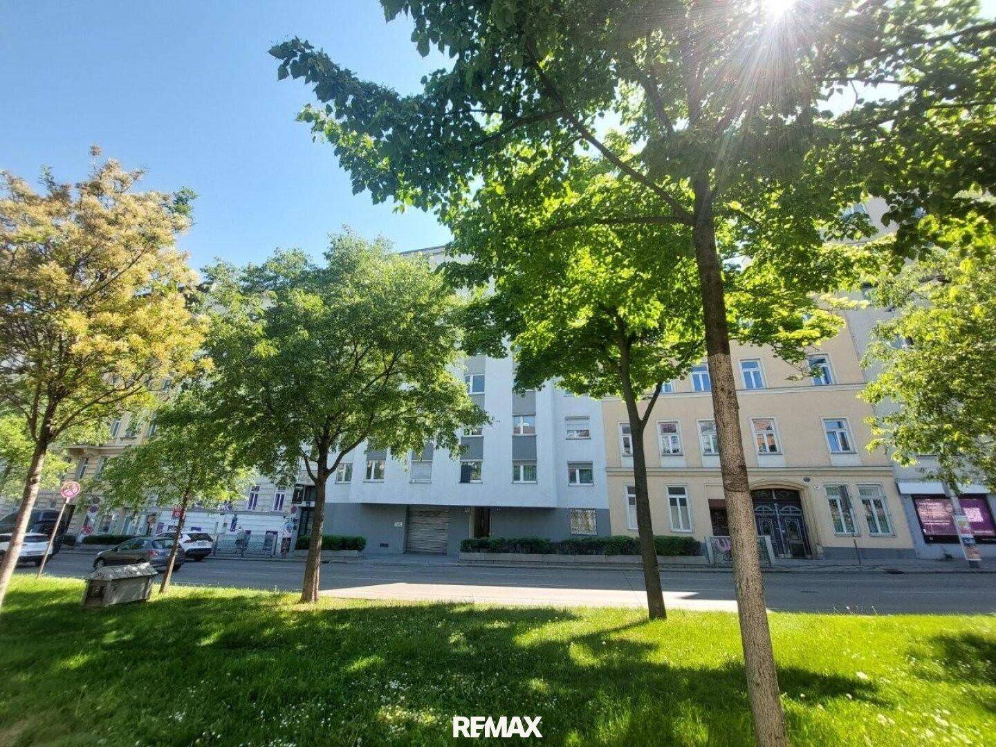 Das Gebäude eingebettet in eine grüne Stadtlandschaft unter strahlend blauem Himmel.