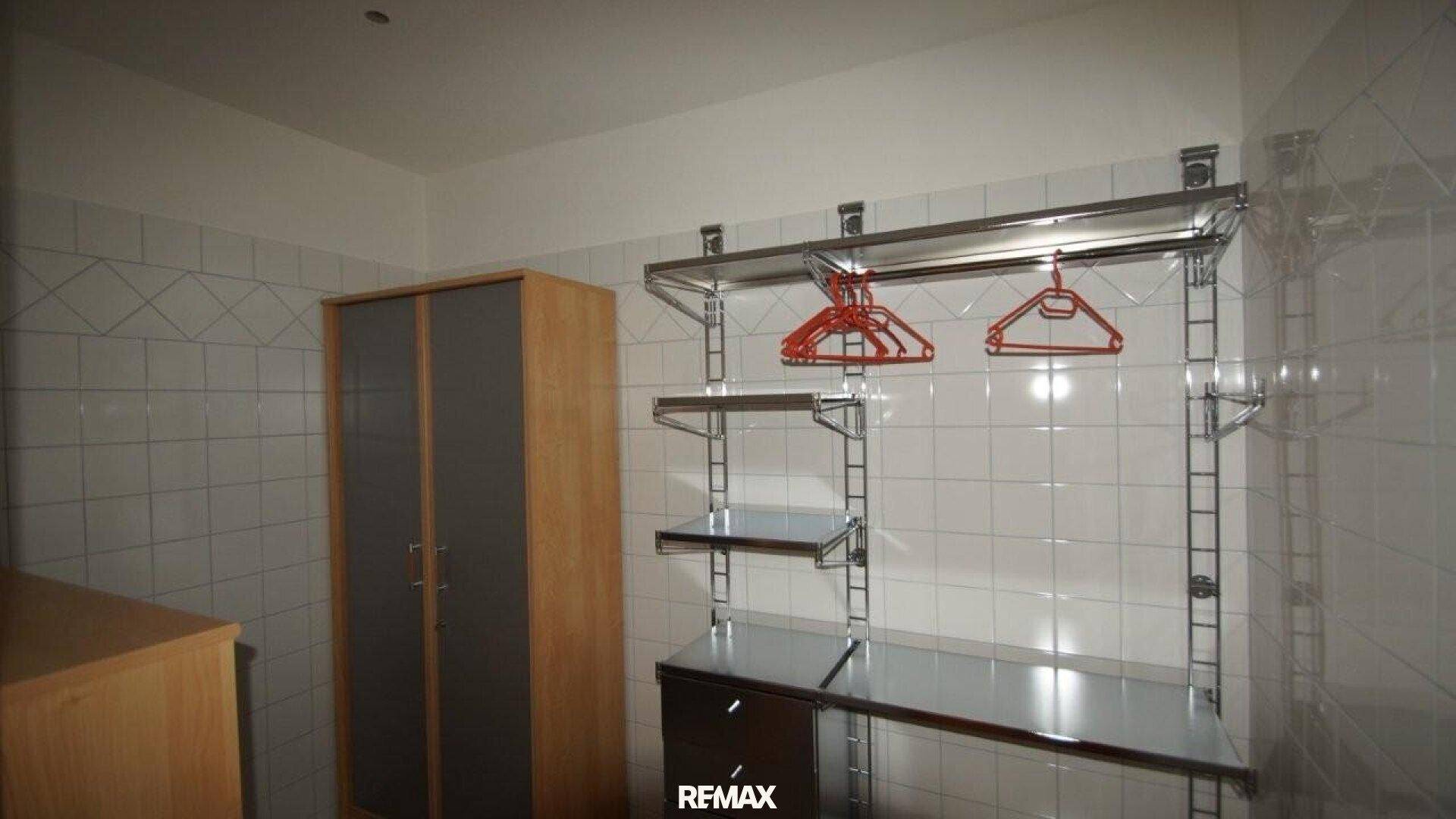 Praktischer Hauswirtschaftsraum mit gefliesten Wänden und robusten Metallregalen für Lagerung.