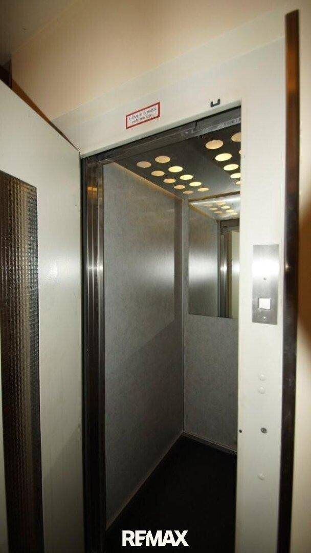 Innenansicht eines Aufzugs mit Metallverkleidung und Deckenbeleuchtung.
