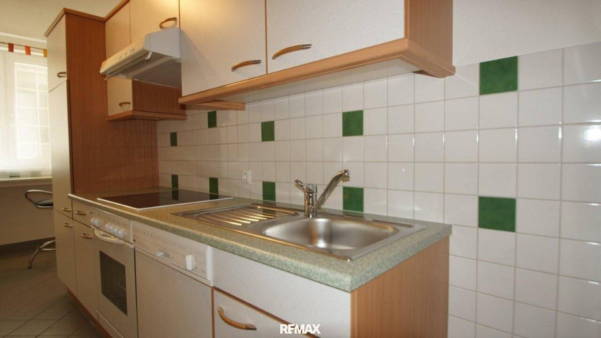Funktionale Küche mit weißen Schränken, Geschirrspüler, Backofen und Spüle.